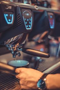 Cropped hand of barista making coffee in cafe