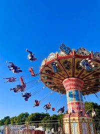 Low angle view of the giant swing against clear blue sky at a summer festival