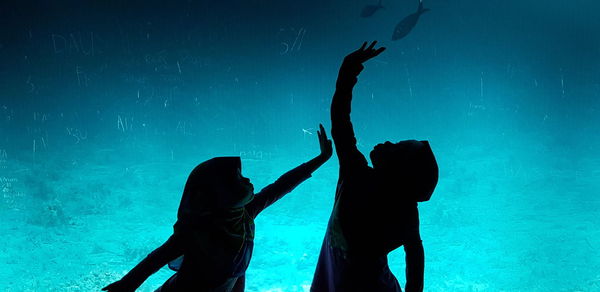 Silhouette children standing in aquarium