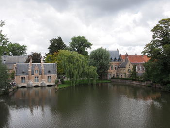 Buildings by river against sky in city
