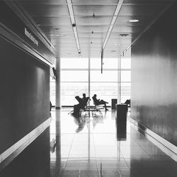 People sitting on chair seen through corridor