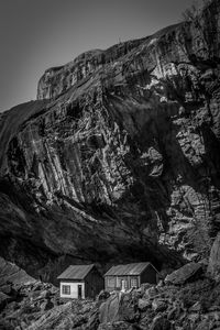 Low angle view of house and rocky mountains against clear sky