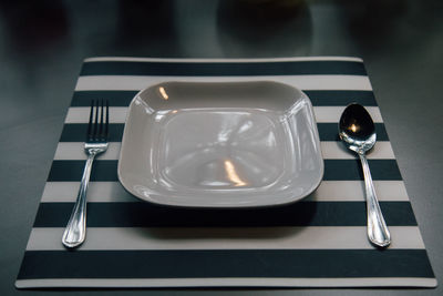 High angle view of empty plate with spoon and fork on table in restaurant