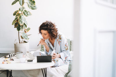 Young woman using digital tablet while sitting on table