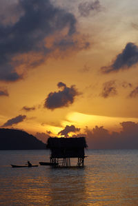 Silhouette boat in sea against orange sky