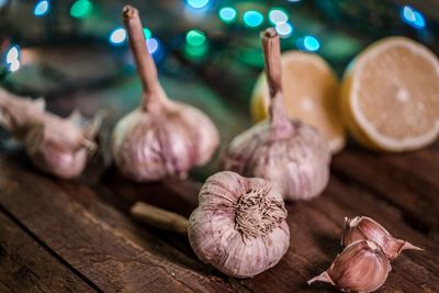 High angle view of garlic with lemon by illuminated string lights on wooden table