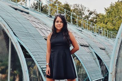 Portrait of beautiful woman standing against bridge