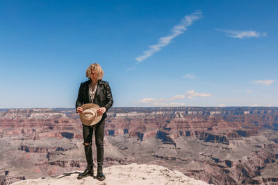 Rear view of man standing on rock against sky