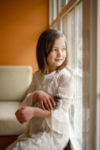 A small happy child with missing tooth holds a baby chick in her arms