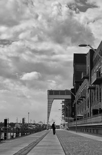 Road passing through city against cloudy sky