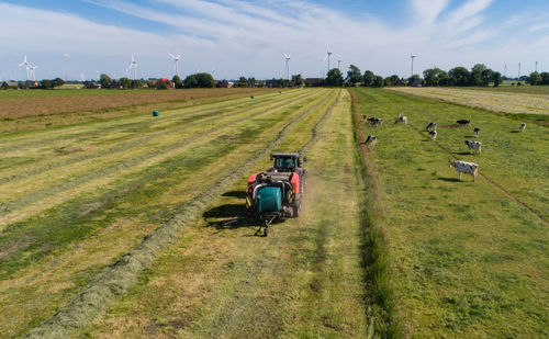 Black tractor with a red straw chamber press during the straw harvest on a mown field