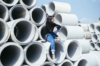 Full length of man on stack of pipes