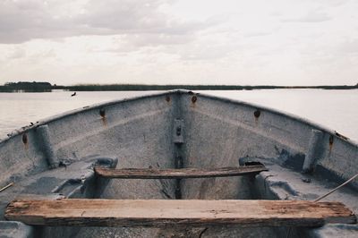 Close-up of rusty boat sailing on water against sky