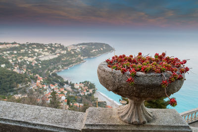 Scenic view of sea by mountain against sky