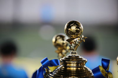 Close-up of golden football shaped trophy against blurred background