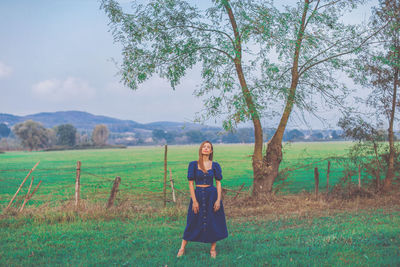 Full length portrait of woman standing on field