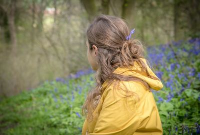 Woman sitting on field against trees