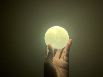 Close-up of hand holding crystal ball against gray background