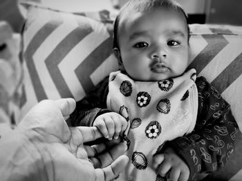 Portrait of cute baby holding hand of father at home