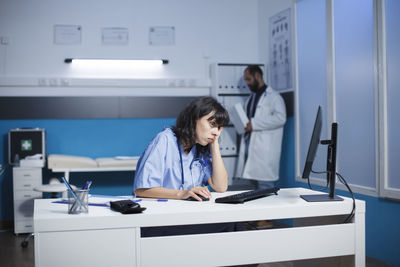 Portrait of young woman using mobile phone in office