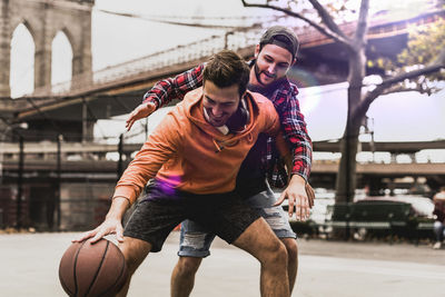 Usa, new york, two young men playing basketball on an outdoor court