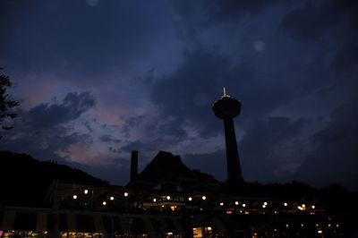 Low angle view of illuminated cityscape against cloudy sky