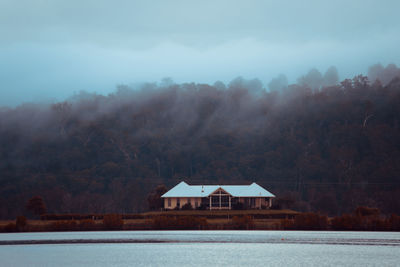 House by lake against sky