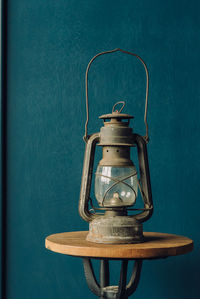 Close-up of lantern on table against blue wall