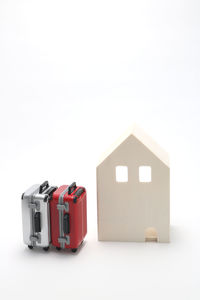 Close-up of model home by small suitcases against white background