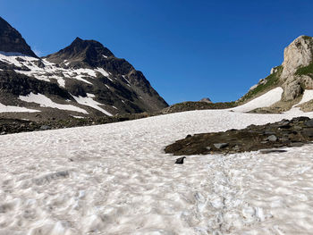 Scenic view of snowcapped mountains against clear blue sky