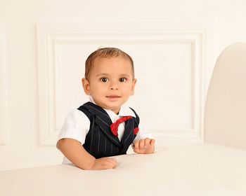 Portrait of cute baby boy by furniture