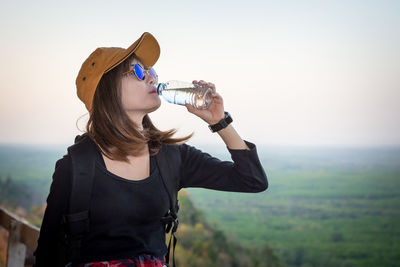 Young woman drinking glass on field