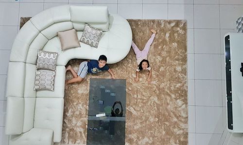 Directly above portrait of siblings lying in living room