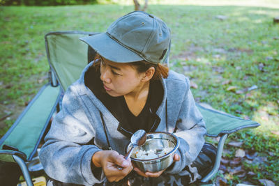 Woman having food while sitting on chair at park