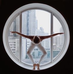 Young woman exercising on window at home