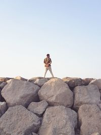 Man standing on rock against sky