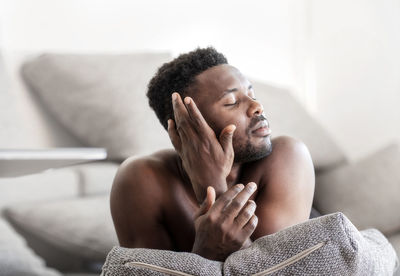 Young man looking away while sitting on sofa