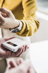 Hand of young businesswoman paying with smart watch on credit card reader