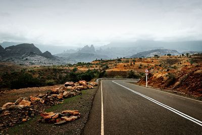 Road leading towards mountains against sky