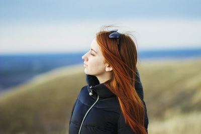 Side view of young woman standing against sea