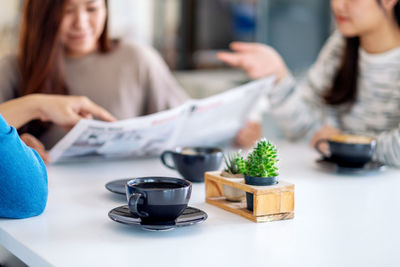 Midsection of woman holding coffee cup on table