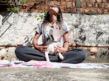 Woman with dog sitting on footpath