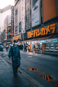 Man in uniform walking on road by buildings in city