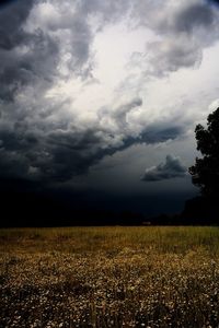 Scenic view of field against storm clouds