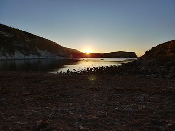 Scenic view of beach against clear sky during sunset