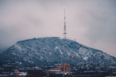 Communications tower and buildings in city against sky