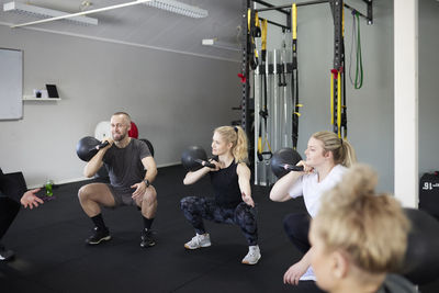 Man and women exercising with kettlebells at health club