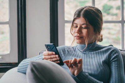Portrait of young woman using mobile phone at home
