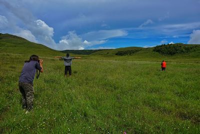 Rear view of men on field against sky