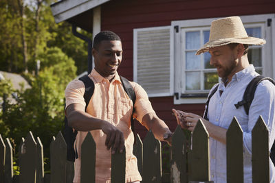 Young men standing near wooden fence